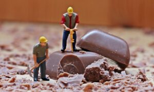 miniature di operai lavorano sopra due quadretti di cioccolata
