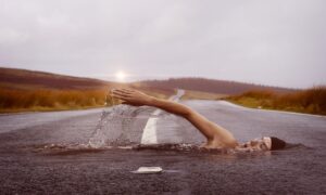immagine illusoria di una donna che sembra nuotare su una strada di cemneto