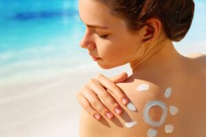 Una ragazza sulla spiaggia si mette la crema da sole
