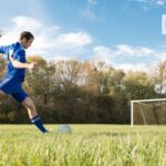 un ragazzo sta per calciare un pallone in porta su un campo di calcio