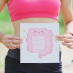 una donna tiene all'altezza dell'addome un cartello con il disegno dell'intestino