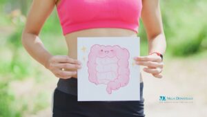 una donna tiene all'altezza dell'addome un cartello con il disegno dell'intestino