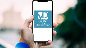 Una mano sostiene uno smartphone che mostra il logo della app My Donatello